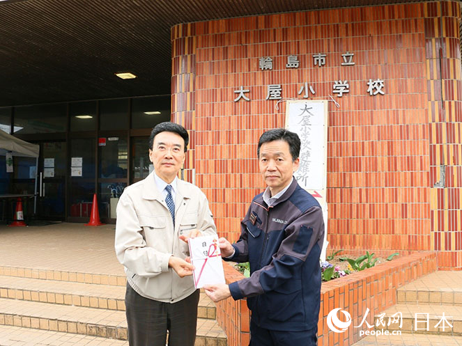在日中企協(xié)會(huì)長(zhǎng)王家馴（左）向當(dāng)?shù)卣ぷ魅藛T轉(zhuǎn)交捐贈(zèng)物資清單。人民網(wǎng) 許可攝