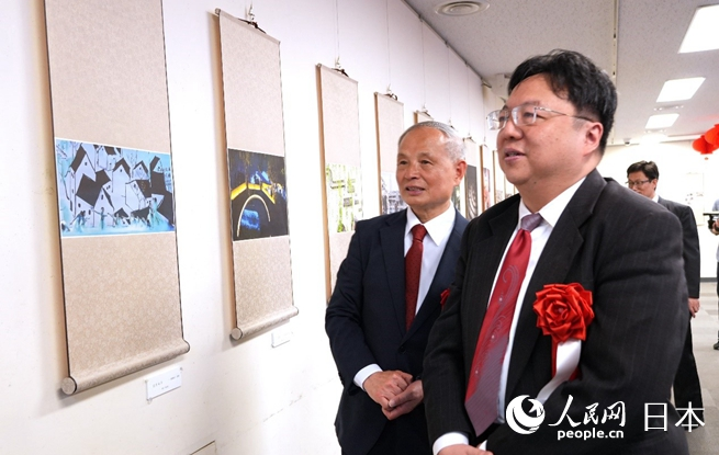 主辦方代表馮學(xué)敏（左）向陳巍總領(lǐng)事（右）介紹展出作品。人民網(wǎng) 許可攝