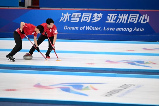 2月13日，日本隊(duì)選手邊見涉（右）和渡邊陽(yáng)紀(jì)在比賽中擦冰。新華社記者 黃博涵 攝