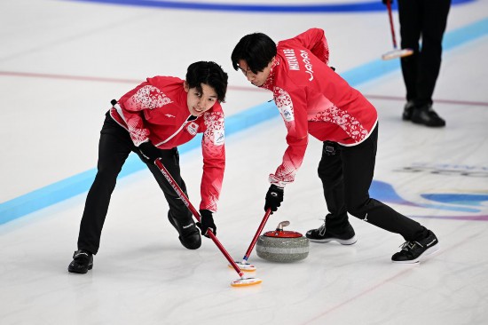 2月13日，日本隊(duì)選手宮櫻介（左）和渡邊陽紀(jì)在比賽中擦冰。新華社記者 黃博涵 攝